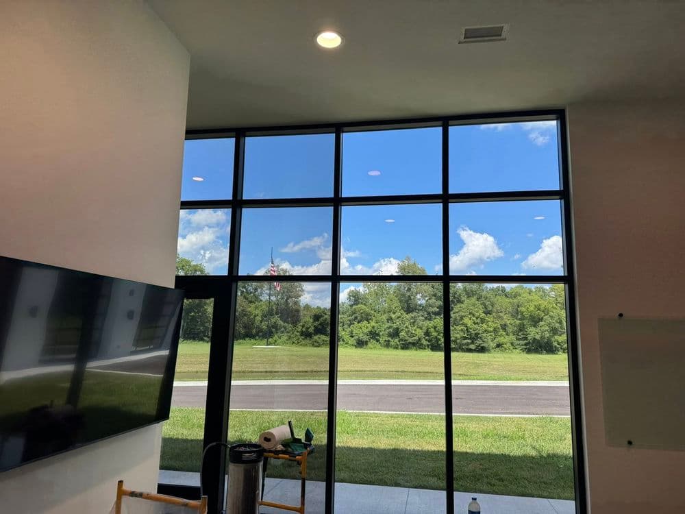 Modern interior featuring large windows with a view of lush greenery and blue sky.
