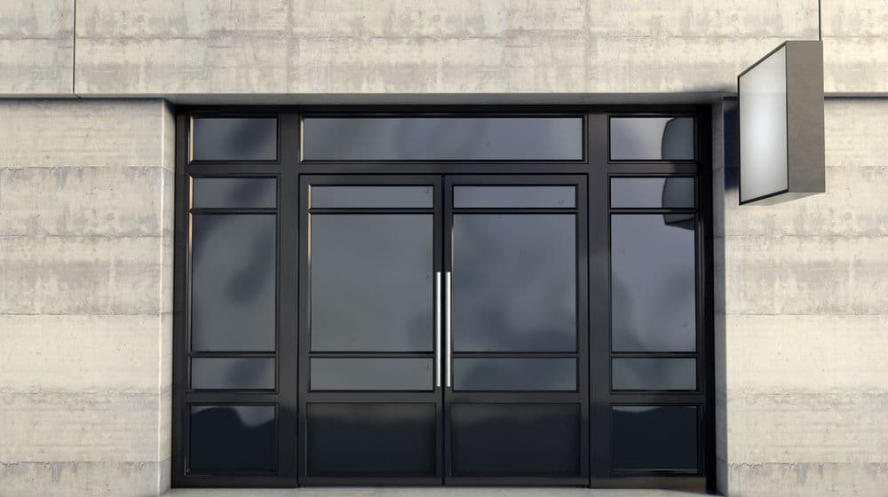 Modern glass storefront with sleek black frames against a concrete wall.