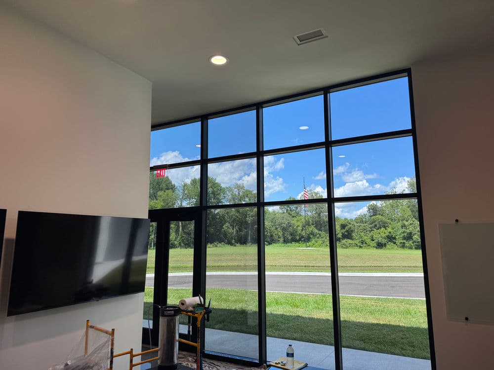 Modern interior with large windows showcasing clear blue sky and greenery outside.